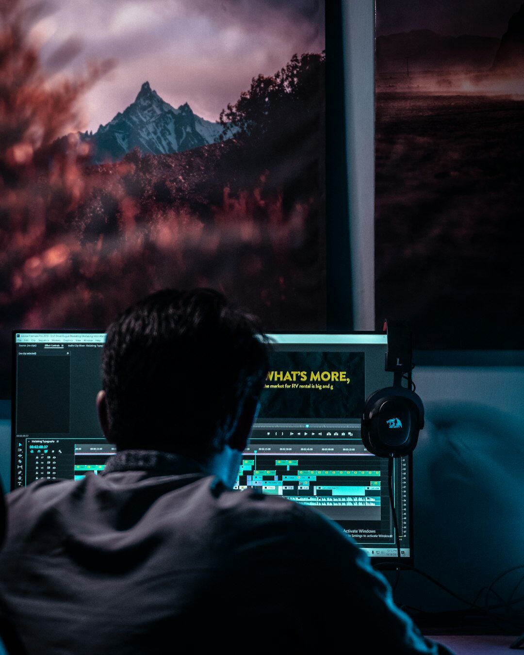 Video editor working at a post-production editing suite with multiple screens